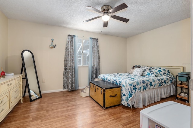 bedroom featuring light hardwood / wood-style floors, ceiling fan, and a textured ceiling