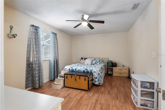 bedroom with a textured ceiling, ceiling fan, and light wood-type flooring