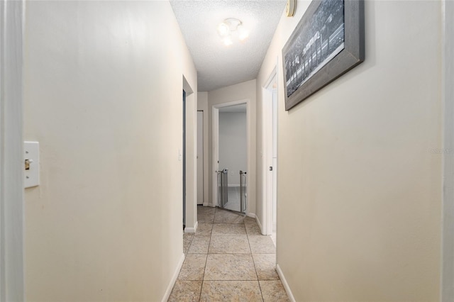 hall featuring light tile floors and a textured ceiling