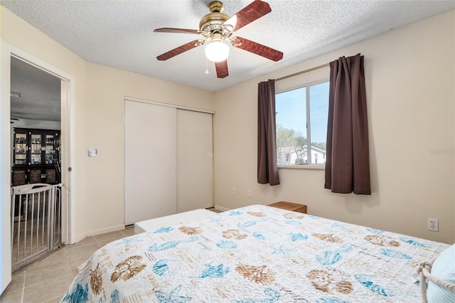 tiled bedroom featuring a closet, ceiling fan, and a textured ceiling