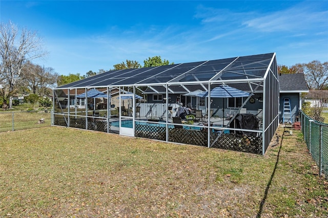 back of house with a lanai and a lawn