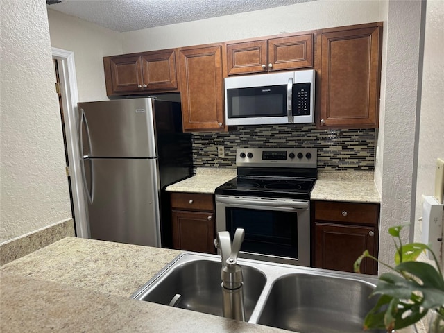 kitchen with decorative backsplash, a textured ceiling, and appliances with stainless steel finishes