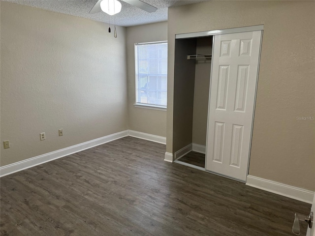 unfurnished bedroom featuring ceiling fan, a closet, dark wood-type flooring, and a textured ceiling