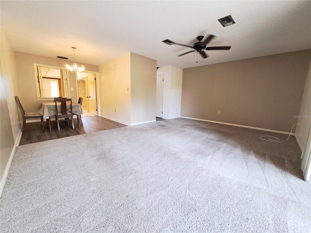 carpeted spare room featuring ceiling fan with notable chandelier