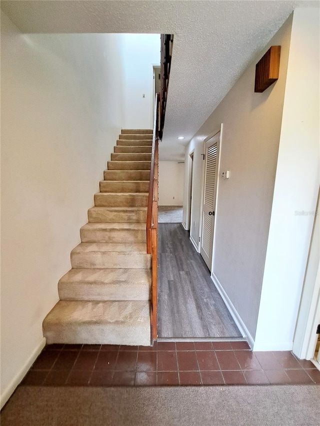 staircase featuring tile patterned floors and a textured ceiling