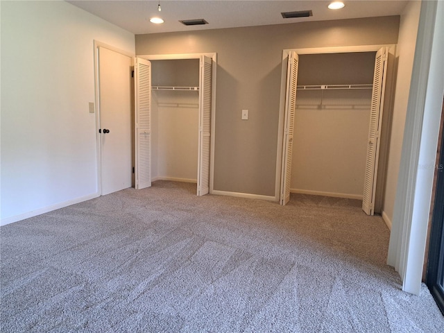 unfurnished bedroom featuring carpet flooring and multiple closets