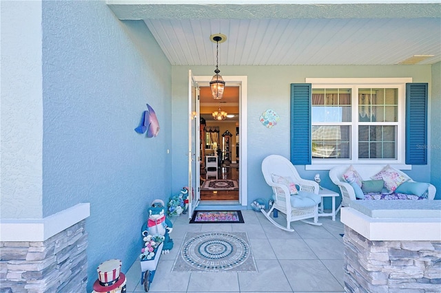 view of exterior entry with covered porch and stucco siding