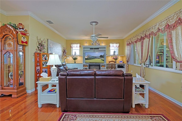 living room with ornamental molding, wood finished floors, visible vents, and baseboards