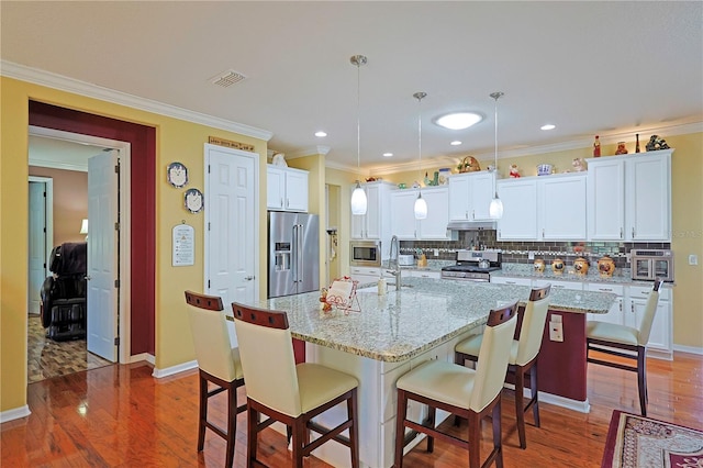 kitchen featuring stainless steel appliances, light wood-style flooring, backsplash, and visible vents