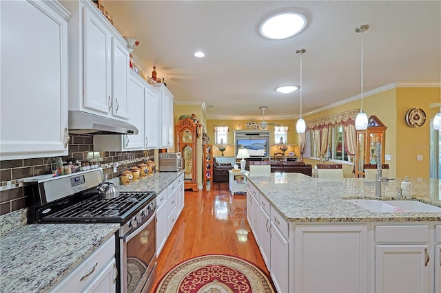 kitchen featuring a sink, gas range, under cabinet range hood, and crown molding