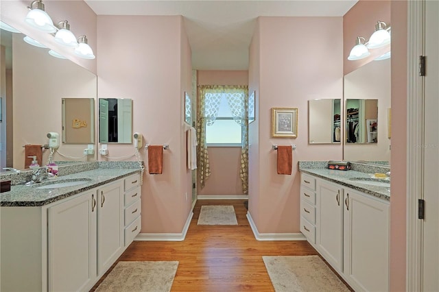 full bathroom featuring baseboards, walk in shower, a sink, and wood finished floors