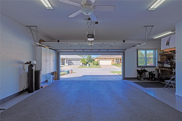 garage featuring concrete block wall, ceiling fan, and a garage door opener