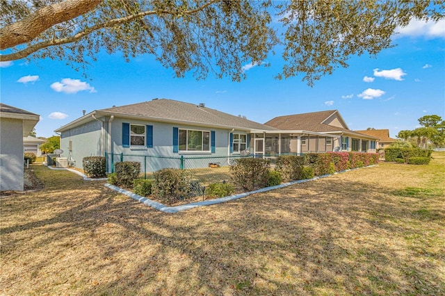 ranch-style house featuring a front lawn, fence, a sunroom, and stucco siding