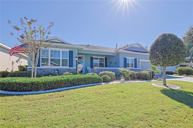 view of front of house with a garage, driveway, stone siding, a front lawn, and stucco siding