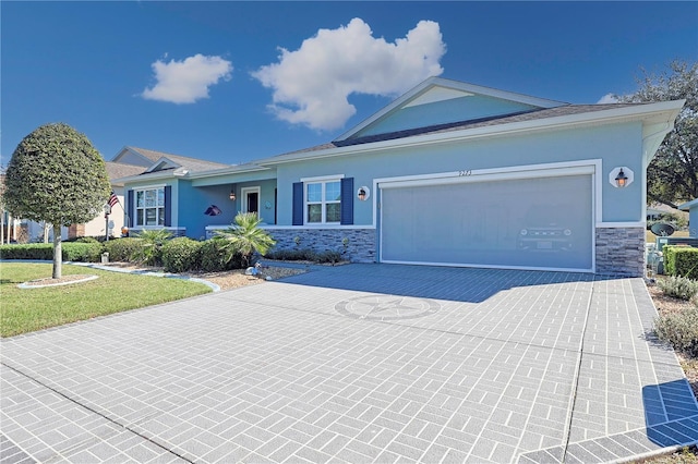 single story home with a garage, stone siding, decorative driveway, and stucco siding