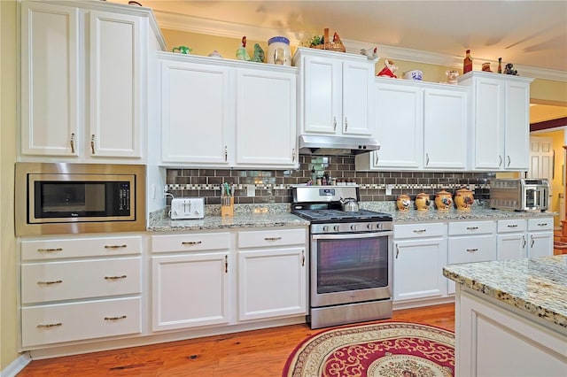 kitchen featuring white cabinets, under cabinet range hood, stainless steel appliances, and decorative backsplash