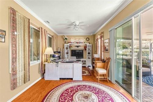 interior space featuring ceiling fan, wood finished floors, visible vents, baseboards, and ornamental molding