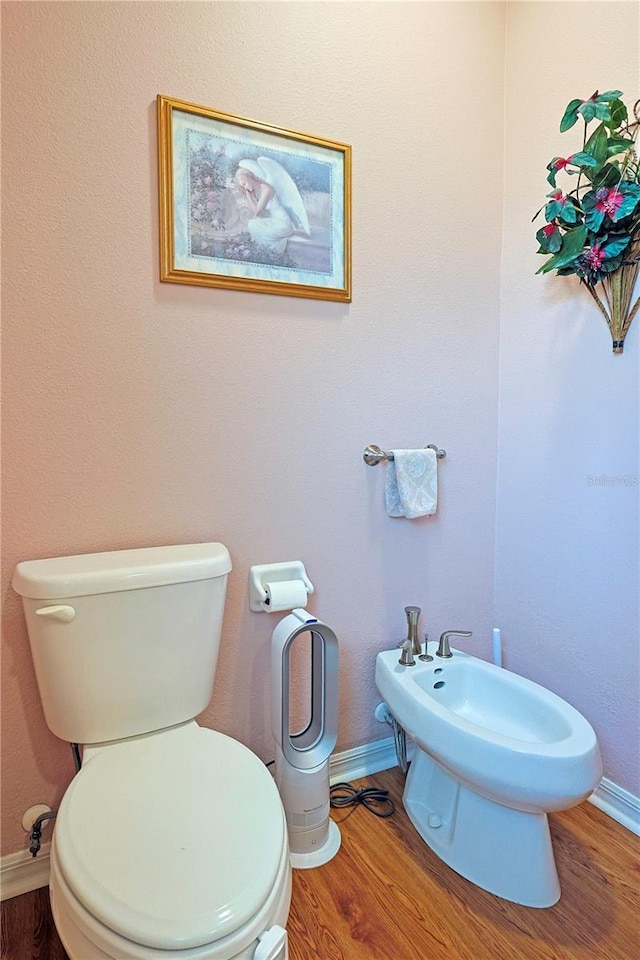 bathroom featuring baseboards, a bidet, toilet, and wood finished floors