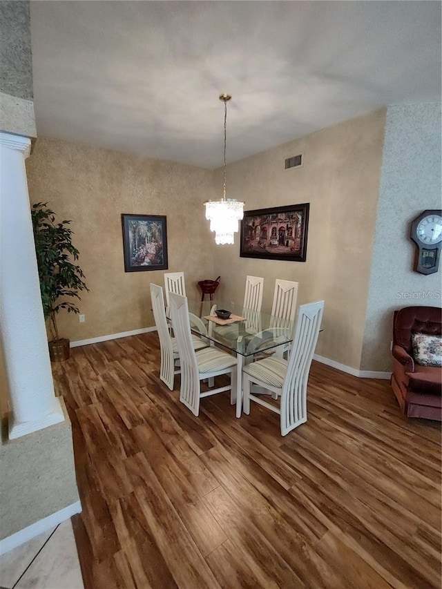 dining area featuring a chandelier, decorative columns, and dark hardwood / wood-style flooring