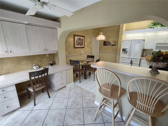 kitchen featuring white appliances, ceiling fan, light tile floors, hanging light fixtures, and backsplash