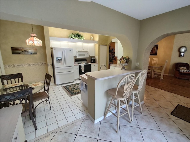 kitchen featuring white appliances, white cabinets, kitchen peninsula, and light tile floors