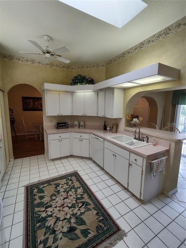 kitchen with a skylight, white cabinetry, and light tile floors