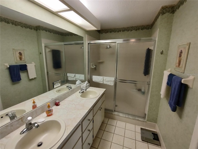 bathroom with tile floors, a shower with door, vanity with extensive cabinet space, and double sink