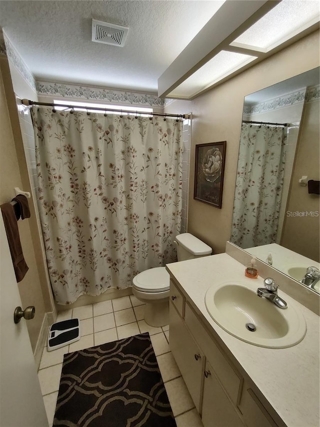 bathroom featuring toilet, a textured ceiling, tile floors, and vanity with extensive cabinet space