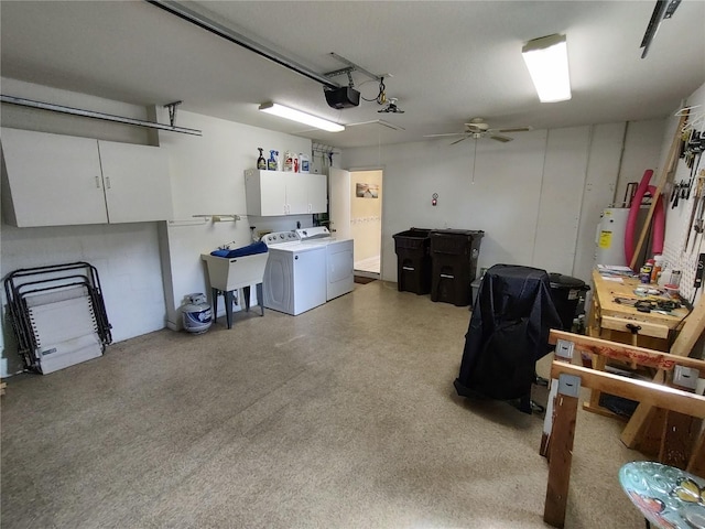 garage featuring gas water heater, a garage door opener, ceiling fan, washer and dryer, and sink