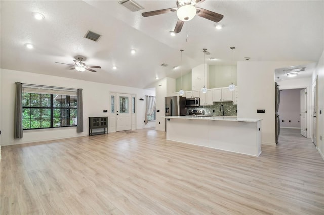 unfurnished living room with high vaulted ceiling, ceiling fan, light wood-type flooring, and sink