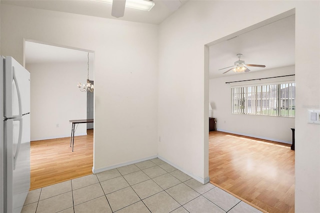 empty room featuring light tile patterned floors and ceiling fan with notable chandelier