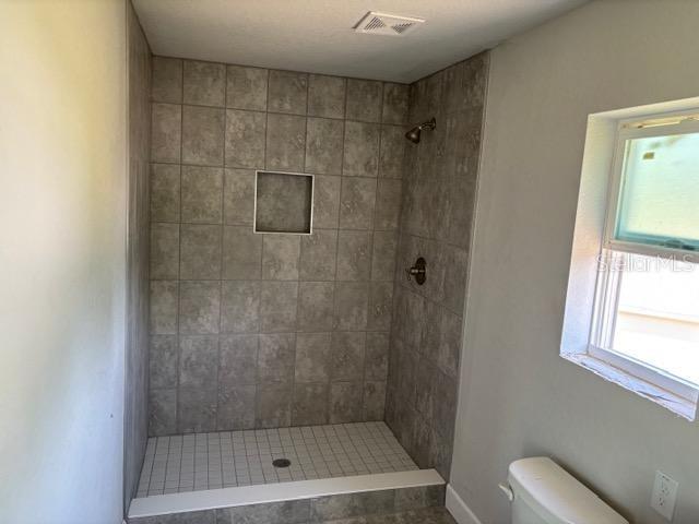 bathroom featuring toilet and tiled shower