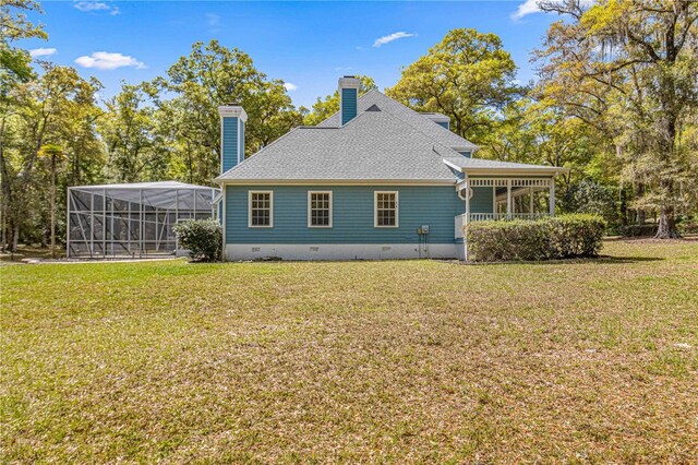 rear view of property with a lawn and glass enclosure