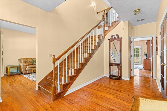 stairs with a textured ceiling and hardwood / wood-style flooring