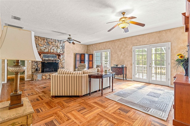 living room featuring a fireplace, ceiling fan, french doors, and a textured ceiling