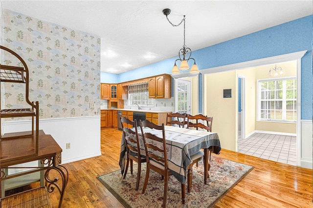 dining room with light wood-type flooring, sink, and an inviting chandelier