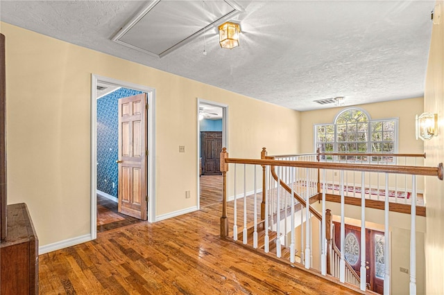 hallway with hardwood / wood-style floors and a textured ceiling