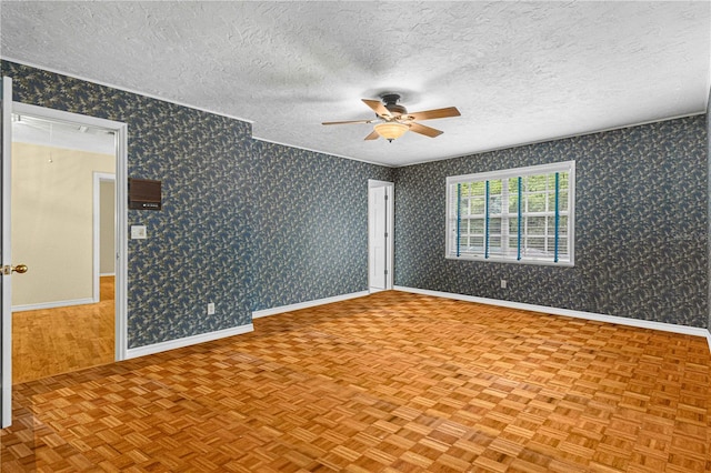 empty room with a textured ceiling, light parquet floors, and ceiling fan