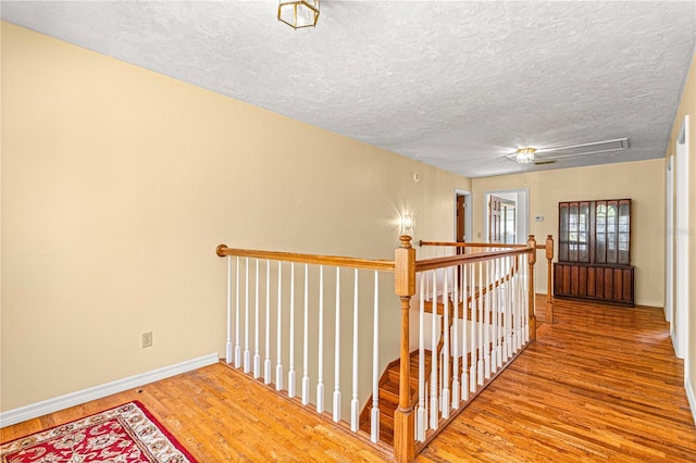 hallway with hardwood / wood-style floors and a textured ceiling