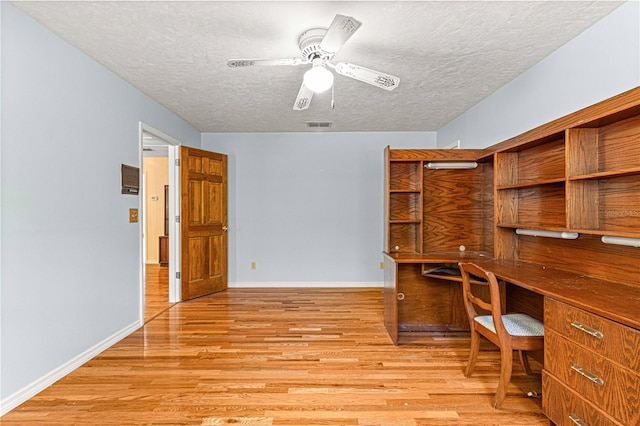 unfurnished office with ceiling fan, light hardwood / wood-style floors, and a textured ceiling