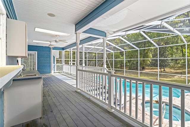 view of swimming pool with a lanai, ceiling fan, sink, and a hot tub