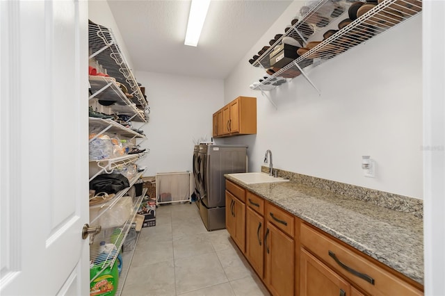 laundry area featuring washing machine and dryer, cabinets, sink, and light tile flooring