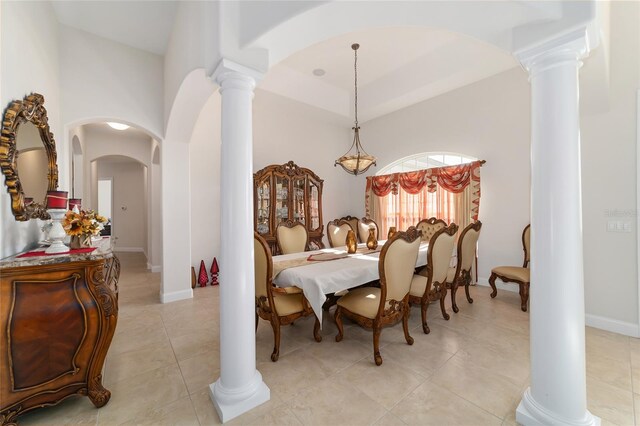 tiled dining area featuring a high ceiling, a chandelier, and ornate columns