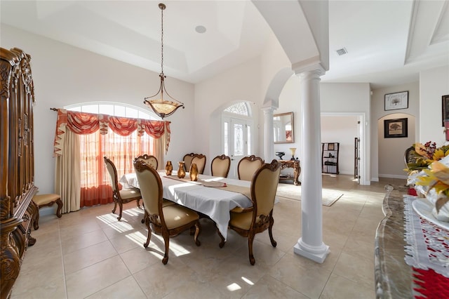 dining room featuring light tile flooring, a raised ceiling, decorative columns, and a wealth of natural light