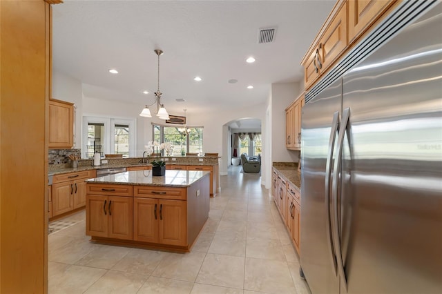 kitchen with pendant lighting, light tile floors, a center island, stone countertops, and appliances with stainless steel finishes