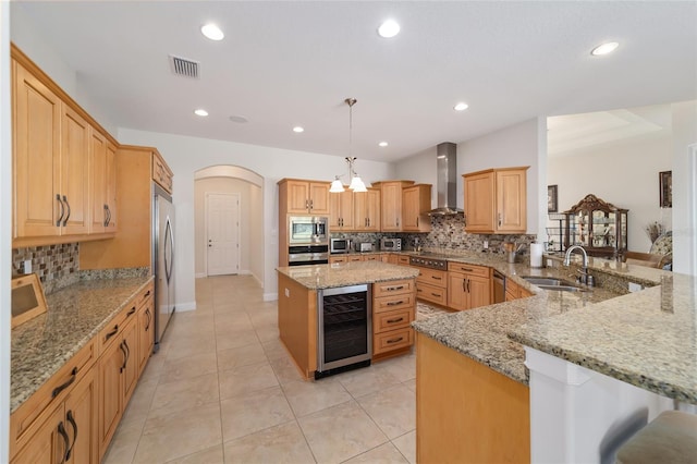 kitchen with light stone countertops, beverage cooler, tasteful backsplash, appliances with stainless steel finishes, and wall chimney exhaust hood