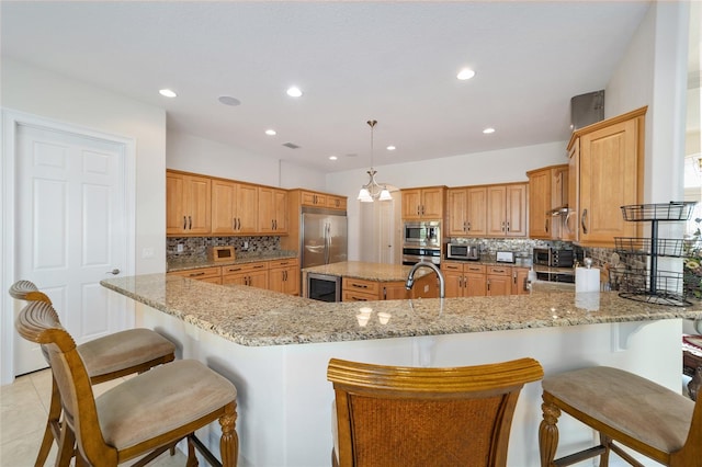 kitchen with light stone countertops, backsplash, a breakfast bar, appliances with stainless steel finishes, and a kitchen island