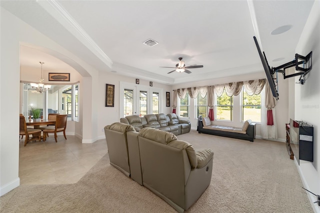 living room featuring crown molding, a tray ceiling, ceiling fan with notable chandelier, and light colored carpet