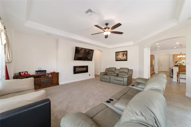 living room with a raised ceiling, crown molding, ceiling fan with notable chandelier, and light carpet