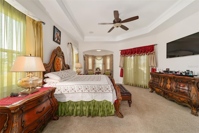 carpeted bedroom with ceiling fan, a raised ceiling, and ornamental molding